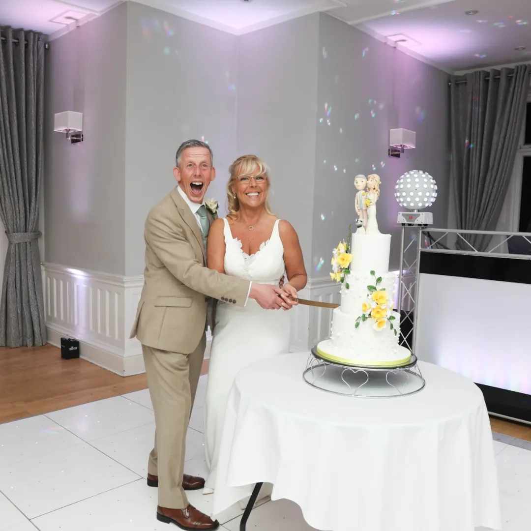 A newly wed couple cutting their bespoke wedding cake.